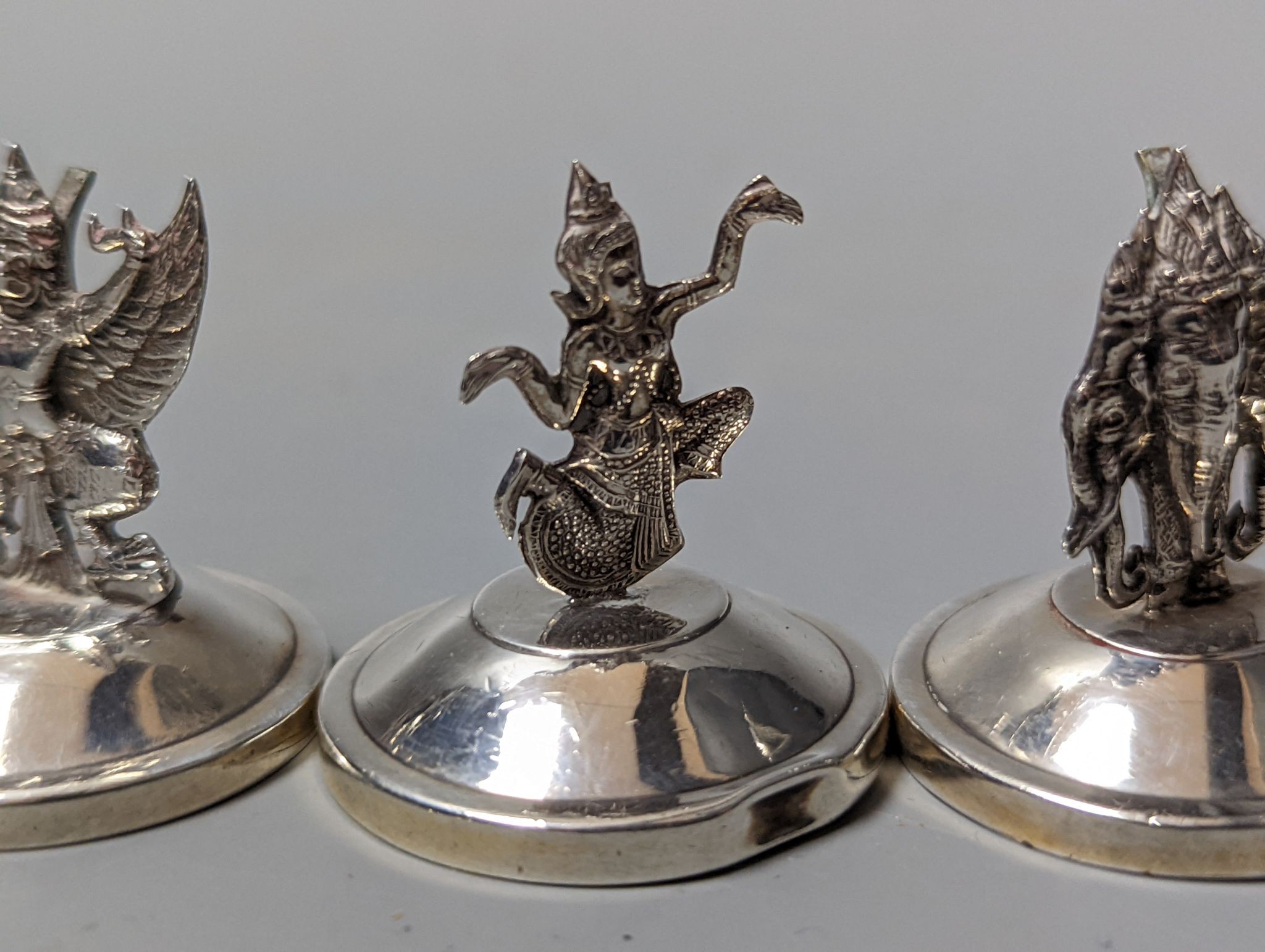 Sixteen assorted Siamese sterling mounted menu holders, modelled with figures, elephant, etc.